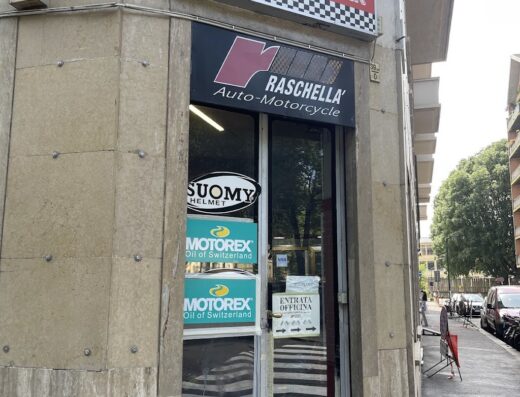 Immagine dell'officina Rascky Auto & Moto s.a.s. con insegna "Riparazioni Auto Moto Scooter", vetrine con marchi Suomy e Motorex, e indicazione "Entrata Officina". Servizi di riparazione moto e scooter.