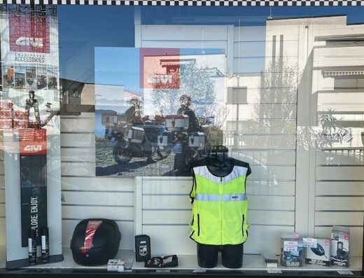 Vetrina del negozio Rea Moto Store con accessori moto GIVI, bauletti, abbigliamento tecnico e foto di motociclisti in viaggio.