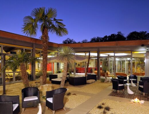 Relais Bellaria Hotel & Congressi: Elegante cortile interno con arredi esterni, palme e illuminazione suggestiva per eventi e relax.