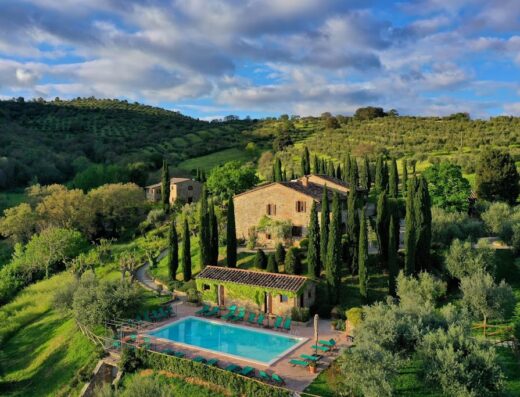 Relais Villa Monte Solare, a luxury wellness and spa retreat in Umbria, Italy, featuring a swimming pool, stone buildings, and lush greenery.