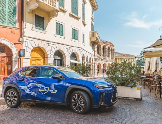 Auto blu Rent4You Verona per noleggio a lungo termine in sosta nel centro storico, con l'Arena di Verona sullo sfondo.