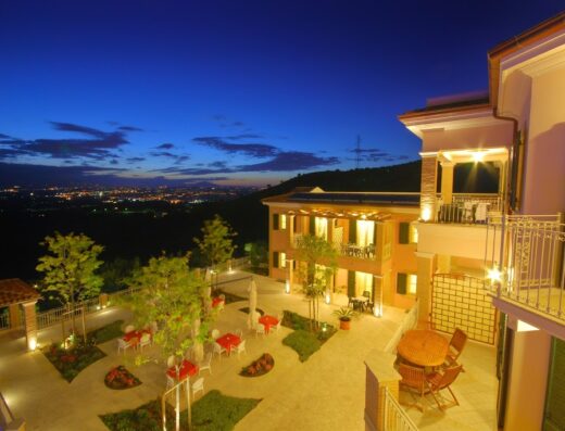 Residence Incantea Resort: Vista notturna della struttura con tavoli all'aperto, balconi illuminati e panorama sulla città.