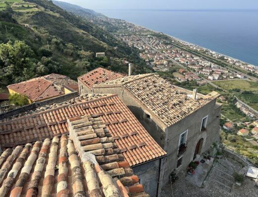 Vista panoramica di Borgodifiume, Italia, con tetti in terracotta, costa, mare e paesaggio collinare sullo sfondo.
