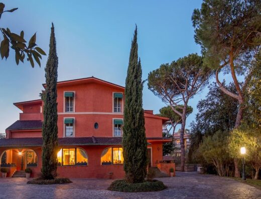 Resort La Rocchetta: Facciata esterna dell'hotel con architettura italiana, alberi di cipresso e illuminazione serale suggestiva