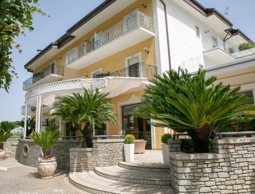 Resort Sant'Angelo & SPA: Esterno dell'hotel con palme nane in vaso, balconi e scalinata in pietra, che conduce all'ingresso.