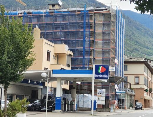 Stazione di servizio Retitalia con edificio in ristrutturazione sullo sfondo, un punto di riferimento per i motociclisti in viaggio.