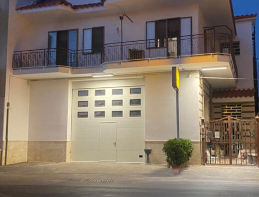 Immagine dell'officina Sco.cons.ARL a Castellana Grotte, specializzata in revisione autoriparatori per moto e veicoli. Facciata illuminata con saracinesca sezionale. Servizi di riparazione e manutenzione.