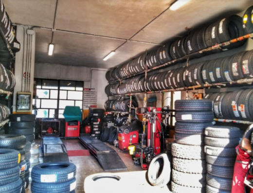 Interno di un negozio Rinaldo Gomme con scaffali pieni di pneumatici per moto e attrezzature per la riparazione e la sostituzione.