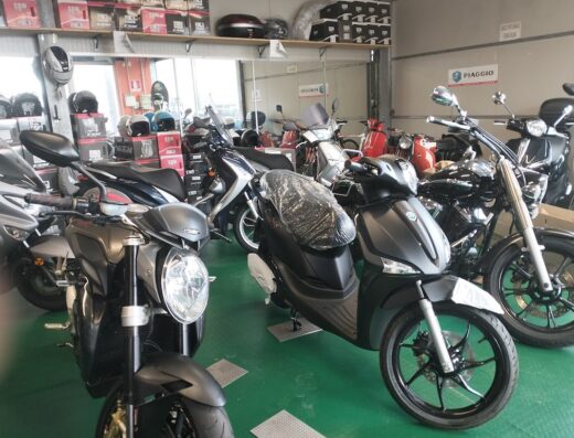 Esposizione di moto e scooter presso Speedy Bike Center: vendita e riparazione di motocicli, inclusi modelli Piaggio. Caschi e accessori visibili.