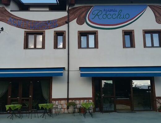 Ristorante Agriturismo Le Caiazzane: Facciata esterna dell'agriturismo con insegna "Azienda Rocchio", tavoli all'aperto e bicicletta parcheggiata, ideale per una sosta durante un viaggio in moto.