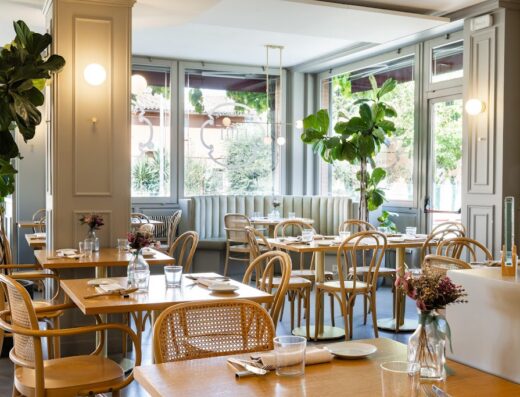 Interno elegante del Ristorante Hotel Emi con tavoli in legno apparecchiati, sedie in rattan, piante decorative e luce naturale.