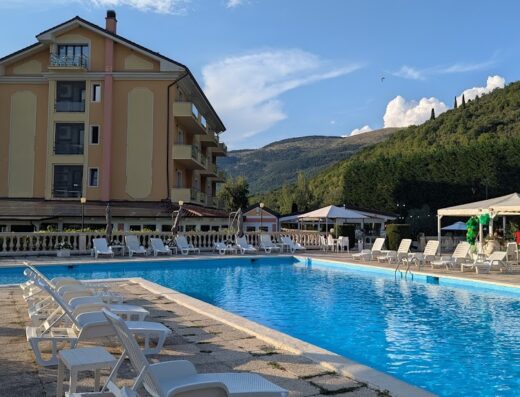 Ristorante Hotel Filippone: Vista della piscina esterna con lettini prendisole, l'hotel e le montagne sullo sfondo.