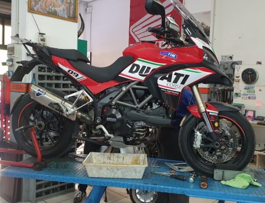 Ducati Multistrada 1200 S Corse in rosso e bianco su un banco da lavoro in un'officina Rivetti Racing. Accessori e manutenzione moto.