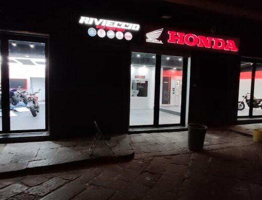 Rivieccio Racing storefront at night, showcasing Honda motorcycles, services, and accessories in Italy. Motorcycle sales and service.