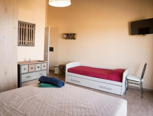 Camera matrimoniale luminosa presso il Room & Breakfast Le Magie, con letto singolo aggiuntivo, armadio in legno chiaro e TV a schermo piatto.