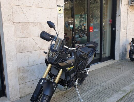 Moto Yamaha Ténéré 700 nera parcheggiata di fronte al negozio Rossi Moto, concessionario e officina specializzata in vendita e assistenza moto Yamaha.
