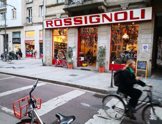 Negozio Rossignoli a Milano con ampia selezione di biciclette, abbigliamento e accessori per ciclisti. Vetrina illuminata e passante in bici.