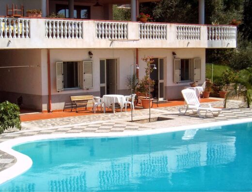 Royal Hotel: Vista della piscina azzurra con sdraio, tavoli e sedie all'esterno dell'hotel, ideale per relax e vacanze.