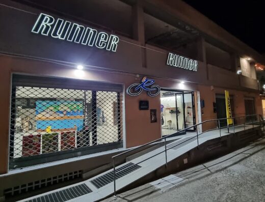 Foto del negozio Runner srl di Vadilonga Alessio & Roberto, rivenditore di moto e accessori. Insegna luminosa "Runner" ben visibile sopra l'entrata con rampa d'accesso.