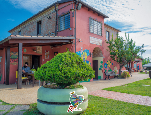 Rurabilandia Fattoria Didattica e Agriturismo Sociale: Veduta esterna dell'agriturismo con decorazioni murali e area relax con persona seduta.
