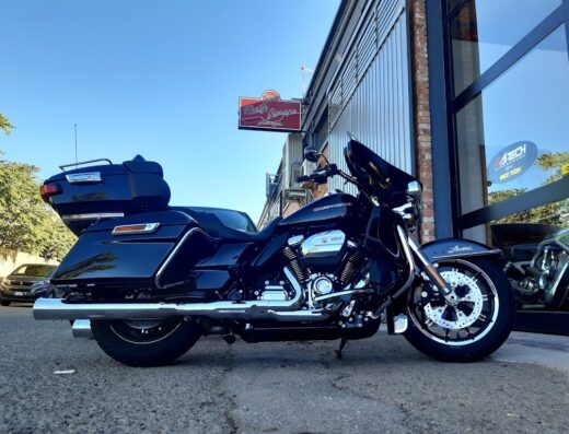 Harley-Davidson nera in posa di fronte al Rusty Garage, officina specializzata in moto custom e accessori per motociclisti.