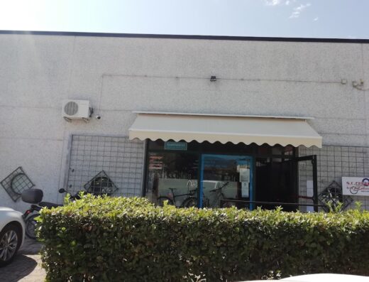 S.C. Centro Bici e Moto: Esterno del negozio con vetrina di biciclette e moto, accessori e ricambi visibili. Servizi di riparazione e vendita.