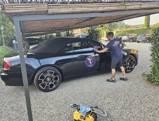 S.o.s. Autolavaggio: uomo lava a mano una Rolls Royce cabriolet nera a domicilio. Servizio professionale di pulizia auto di lusso.