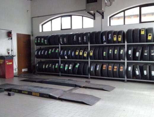 Interno di Salzano Gomme con scaffali pieni di pneumatici per moto e auto, e ponte sollevatore per il servizio di cambio gomme.