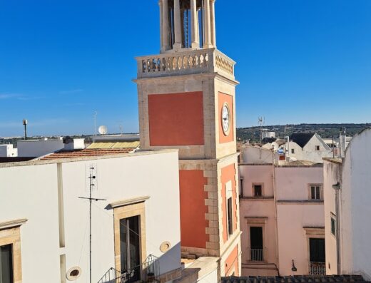 Veduta aerea del campanile storico del Santarosa Relais, con architettura tradizionale e cielo blu sullo sfondo, Ostuni, Puglia.