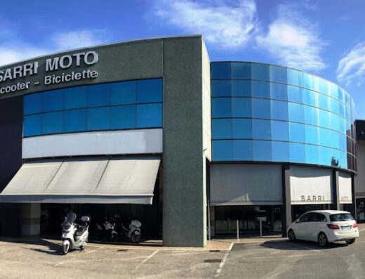 Sarri Moto Oderzo dealership featuring motorcycles, scooters, and bicycles with a modern building design and customer parking.