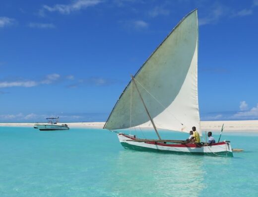 Immagine di una barca a vela tradizionale con persone a bordo che naviga in acque cristalline, parte di un'esperienza di viaggio Saudage Viaggi.