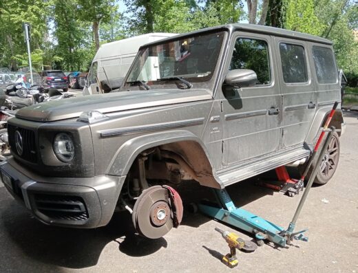 Mercedes-Benz Classe G grigia sollevata con cric per la sostituzione delle ruote; manutenzione auto e accessori Savimoto.