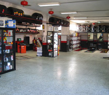 Interno di Schiavi Gomme, officina specializzata in pneumatici per moto, con scaffali pieni di gomme e attrezzature per la riparazione.