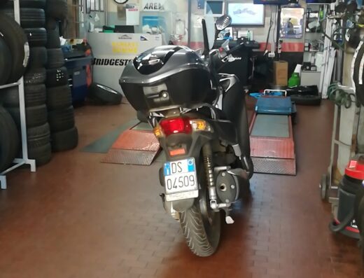 Schiavi Gomme Via Vermicino: interno dell'officina con moto pronta per il servizio gomme, sullo sfondo scaffali con pneumatici Firestone e Bridgestone.