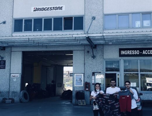 Tre persone posano davanti a Spiezia Tyres, con accessori moto e abbigliamento, probabilmente acquistati nel negozio di pneumatici e accessori per motociclisti.