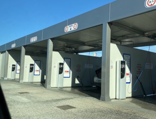 File di box per l'autolavaggio moto Self Wash Genius, con colonnine di pagamento e cartelli "Pista 4" e "2.5", per la pulizia fai da te di moto e scooter.