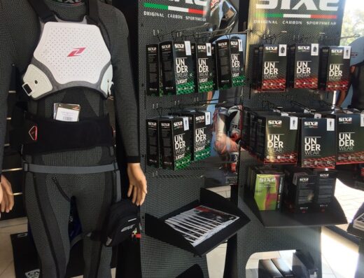 Manichino con abbigliamento tecnico moto SIX2: protezione torace bianca, intimo termico grigio e accessori. Espositore con prodotti underwear light SIX2.