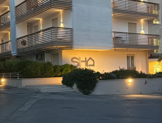 Edificio SHA illuminato di sera, con balconi e vegetazione. Design moderno e accogliente per viaggi e soggiorni.