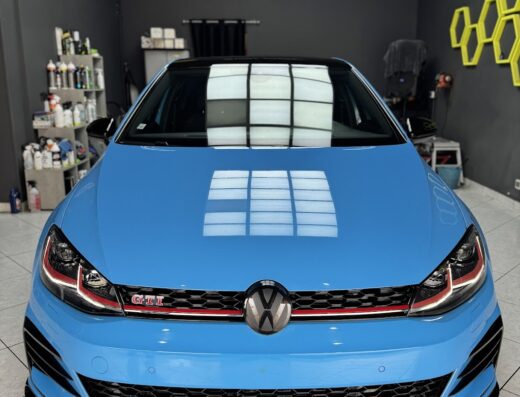 Auto Volkswagen Golf GTI blu brillante presso Shiny Garage Trapani, dettaglio frontale con logo VW e griglia prominente. Servizi di detailing auto e cura estetica.
