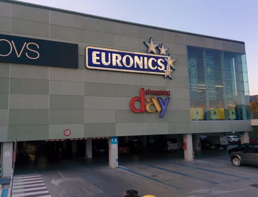 Foto dell'ingresso di un centro commerciale con i marchi OVS e Euronics, indicando un giorno di shopping con parcheggio sotterraneo.