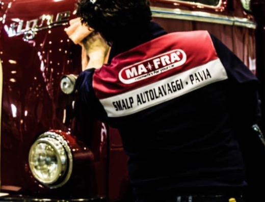 Dettaglio di un addetto di Smalp Autolavaggi a Pavia che lucida la carrozzeria di un camion d'epoca rosso bordeaux con prodotti MA-FRA.