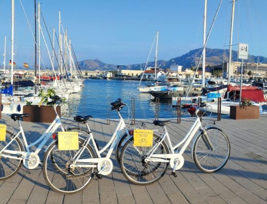 Tre biciclette bianche in sosta al porto turistico di Palermo, pronte per il noleggio e un tour in bici. Noleggio bici per esplorare la città.