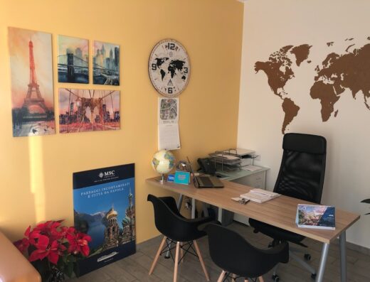 Ufficio luminoso con scrivania, sedia, mappamondo, orologio e quadri di Parigi e New York, ideale per pianificare viaggi e avventure da SpeakSicily.