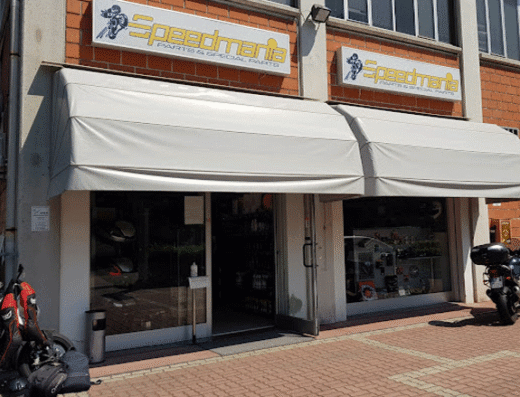 Speedmania negozio di ricambi e accessori moto: Facciata del negozio Speedmania con vetrine che espongono caschi e accessori per motociclisti.