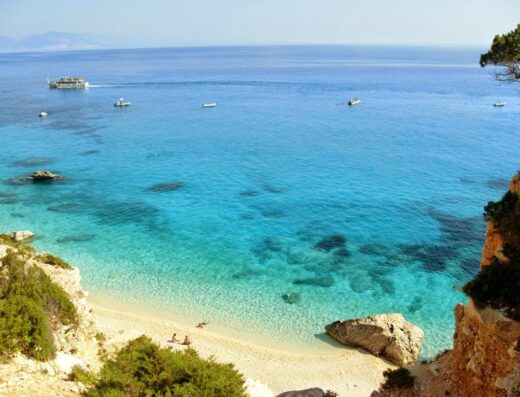 Splendida vista aerea di Cala Luna, Sardegna, con spiaggia bianca, mare cristallino e barche. Perfetta per viaggi e vacanze avventura.