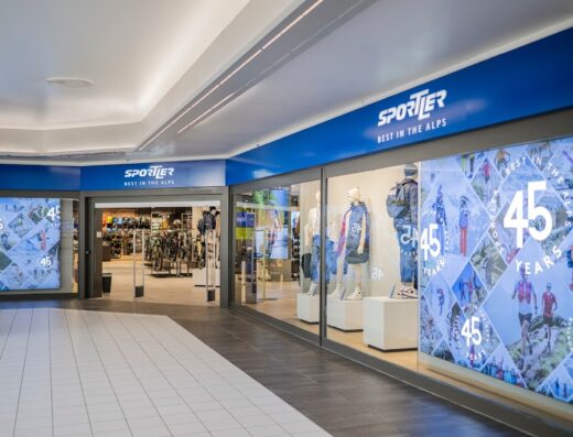 Ingresso del negozio Sportler, specializzato in articoli sportivi, con vetrine che espongono abbigliamento e accessori per attività all'aperto e montagna, celebrando il 45° anniversario.