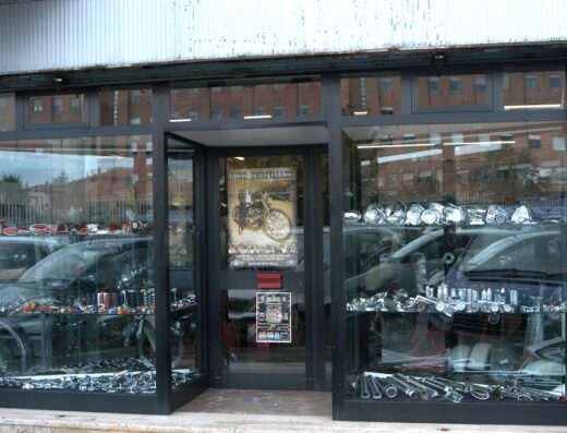 Vetrina del negozio SPQR Moto con accessori e ricambi per moto custom e d'epoca. Poster di moto vintage visibile in negozio.