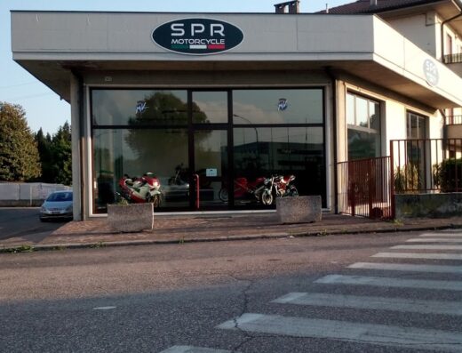 SPR Motorcycle store front in Italy with motorcycles visible through the large glass windows; motorcycle marketplace, services.
