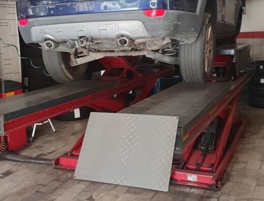 Auto blu Chevrolet Captiva sollevata su un ponte elevatore in un'officina per la riparazione e la manutenzione di veicoli. Gomme visibili sullo sfondo.