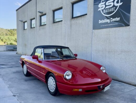 Un'Alfa Romeo Spider rossa decappottabile parcheggiata di fronte all'SSC Garage, centro specializzato nel detailing auto e servizi per auto d'epoca.